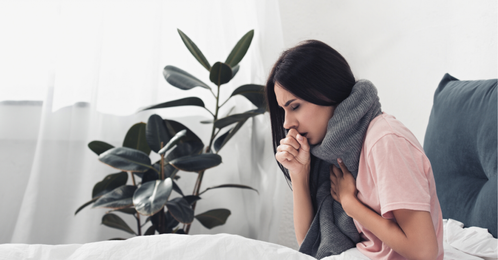 Woman coughing while wearing a large grey scarf